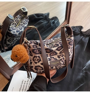 Detail of leopard print half-moon canvas bag with brown PU strap and teddy bear charm