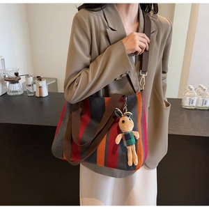 Detailed side view of large striped canvas tote bag with a cute plush rabbit charm