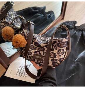 Detail of leopard print half-moon bag with leather logo tag and plush puppy charm