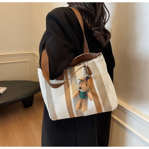 Detail view of canvas tote bag with brown stripes and a cute plush rabbit pendant charm