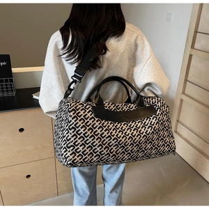 Detailed view of large capacity duffle bag with geometric pattern worn on shoulder
