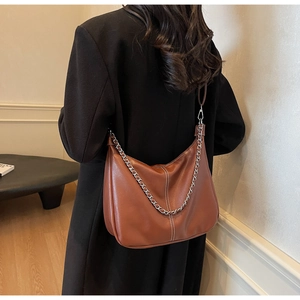 Detail einer braunen Hobo-Tasche aus Leder mit weißen Nähten und silberner Kette