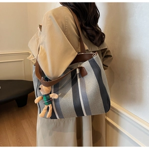 Detailed texture of striped woven tote bag with a cute bear pendant on shoulder strap