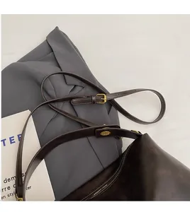 Detail of dark brown faux leather shoulder bag with slim adjustable strap and metal hardware
