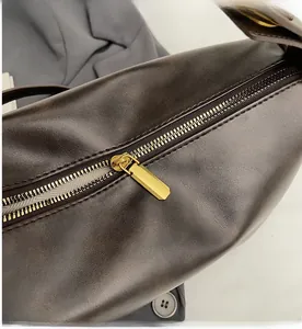Macro shot of high-quality smooth gold metal zipper on a dark brown leather tote bag