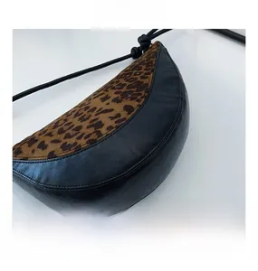 Detail shot of leopard print suede and black leather stitching on a half-moon bag