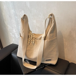 Nahaufnahme der beigen Nylon-Tragetasche mit MACHUGE-Label und Knotendetail am Zipper