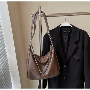 Detail einer braunen Leder-Hobo-Tasche mit Silberkette und verstellbarem Schultergurt