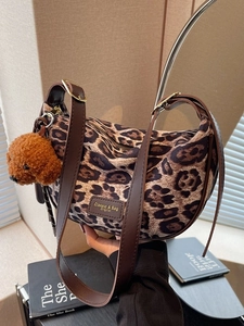 Leopard print crescent shoulder bag with brown leather strap and plush dog charm
