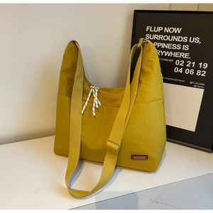 Detail einer leuchtend gelben Nylon-Tragetasche mit Vordertasche und verstellbarem Gurt