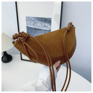 Detail of a brown suede and smooth leather crescent bag with a unique knotted shoulder strap
