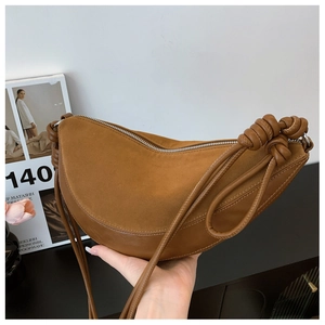 Detailed close-up of a brown leather crescent bag with unique knot shoulder strap detail