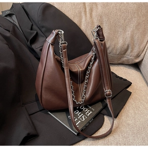 Detail der braunen PU-Ledertasche mit weißen Kontrastnähten und klobiger Silberkette
