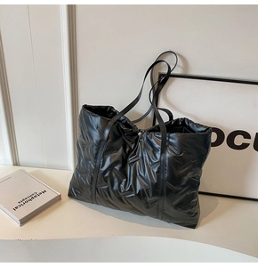 Detail der schwarzen gesteppten Puffer-Tasche mit glänzendem Material und Lederriemen