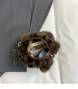 Détail de l'intérieur du sac seau léopard en peluche contenant téléphone et maquillage