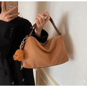 Detailed texture of brown suede tote bag with cute teddy bear charm on model