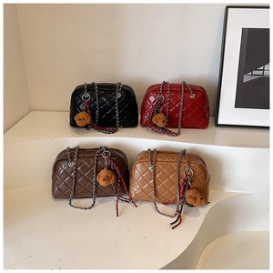 Close-up of four quilted pillow bags in black, red, and brown with chain straps