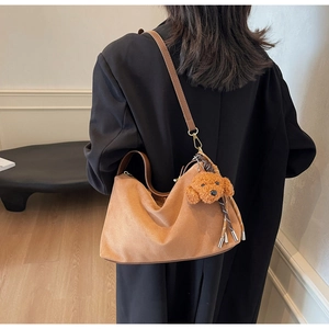 Brown suede hobo shoulder bag with leather strap and plush teddy bear charm detail