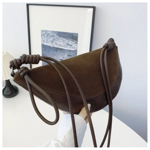 Macro detail of the dark brown suede and smooth leather patchwork on the crescent bag