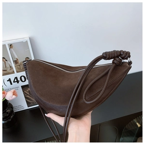 Detail of a dark brown half-moon crossbody bag with a unique woven knot shoulder strap