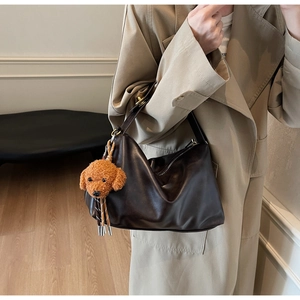Detail view of coffee brown faux leather tote bag with cute plush puppy keychain accessory