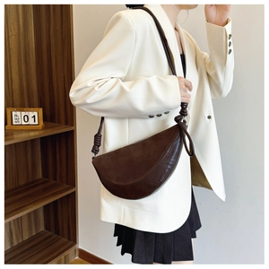 Detail of dark brown dumpling bag with unique knot design on the shoulder strap