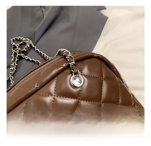 Detail of dark brown quilted pillow bag with silver chain strap and metal eyelets