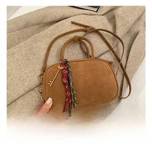 Détail du sac cabas en daim marron avec gaufrage de la marque et breloque clé dorée