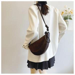 Detail view of the brown crescent bag with a decorative knotted shoulder strap detail
