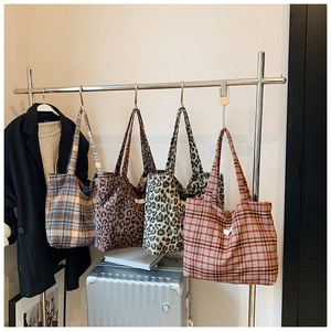 Detail of four tote bags in plaid and leopard patterns hanging on a metal hanger