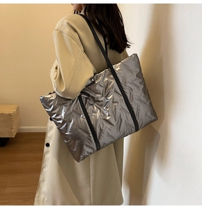 Makro-Detail der silbernen gesteppten Tasche mit Metallic-Textur und schwarzen Trägern