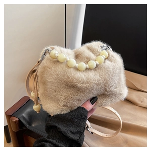 Détail du sac seau en fausse fourrure beige avec poignée en perles et bandoulière en cuir