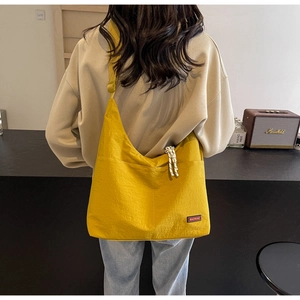 Details einer gelben Nylon-Tragetasche mit verstellbarem Riemen und Markenlogo