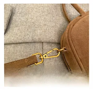 Vue détaillée du crochet métallique doré sur un sac vintage en daim marron