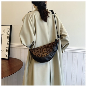 Detail of leopard print patchwork on a black leather crescent shoulder bag with knot strap