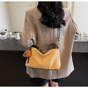 Brown suede hobo bag with a cute puppy plush charm shown on a model in a cafe