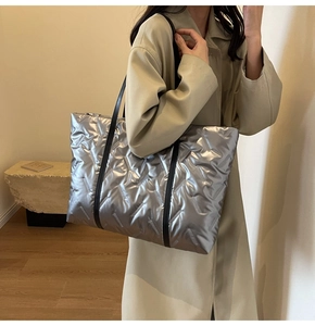 Detailansicht der silbernen Stepptasche mit V-Nähten und schwarzen Trägern am Model