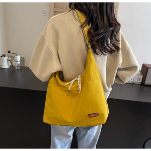 Detail einer großen gelben Hobo-Tasche mit gewebtem Seildekor und Markenetikett-Logo