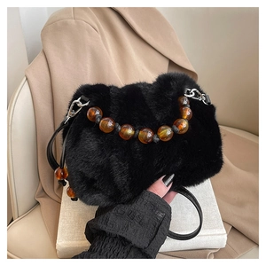 Détail du sac seau en fausse fourrure noire avec poignée en perles ambrées et crochets argentés