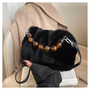 Détail du sac seau noir en fausse fourrure avec perles ambrées et bandoulière cuir