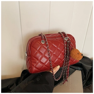Detail of red quilted pillow bag featuring silver chain strap and bear charm