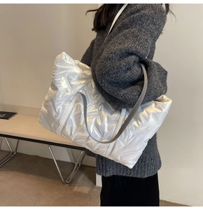 Detail der perlweißen Puffer-Tasche mit V-Steppung an der Schulter des Models gezeigt
