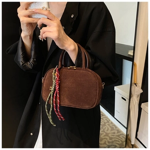 Détail du sac à main rétro en daim marron avec gaufrage et cordon bicolore décoratif