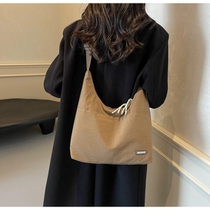 Detail der khakifarbenen Hobo-Tasche mit Stofftextur und weißem Etikett in der Rückansicht