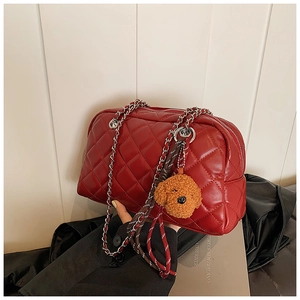 Detail of red quilted leather pillow bag with silver chain and brown plush bear charm