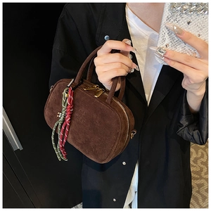 Détail d'un sac à main en daim marron foncé avec corde tressée et accents dorés