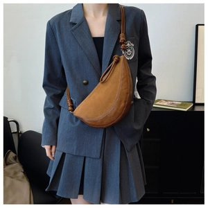 Detail of a brown crescent crossbody bag with mixed suede texture and knotted rope strap