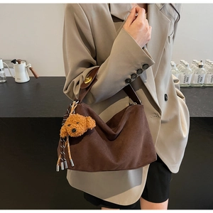 Detail of coffee brown suede hobo bag with teddy bear pendant and woven tassel decoration