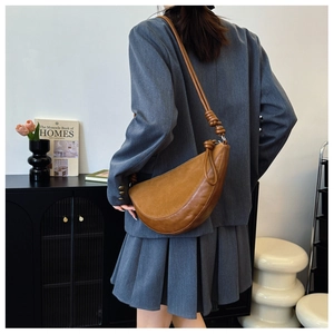 Detailed view of brown leather half-moon shoulder bag with unique knotted strap design