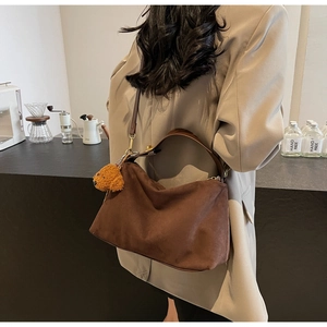 Brown suede crossbody bag with teddy bear charm on model in business casual outfit